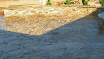 Custom stone patio with seating wall created by Ambiance Landscape in Brandon, MS.